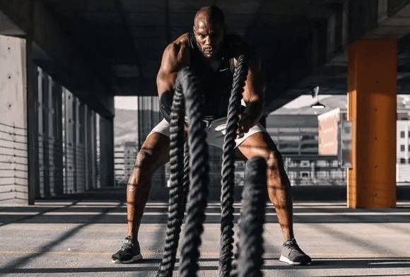 Athletic man using battle ropes.